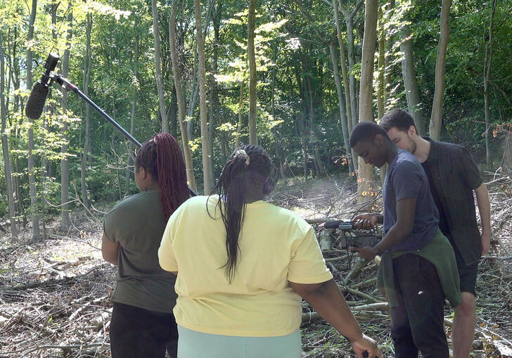 4 individuals stood in the woods with filming equipment 