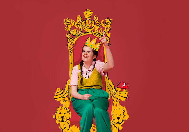 A photo of Rachel sitting on an illustrated golden throne wearing an illustrated golden crown. She is wearing green trousers and a pink top with a yellow top on top of it.  She is smiling with her finger pointed towards the sky.