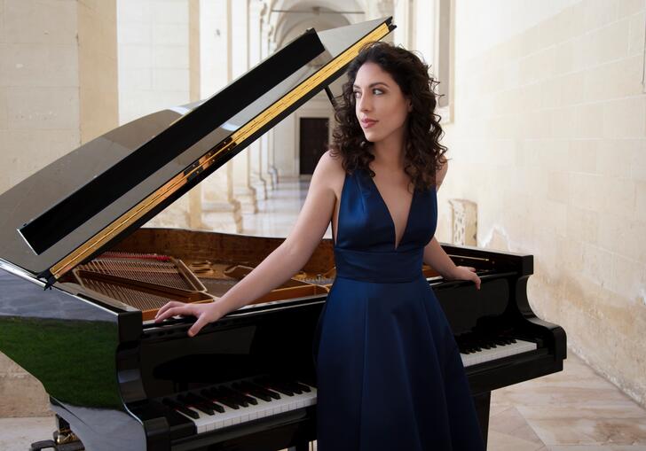 Beatrice Rana standing in front of a grand piano