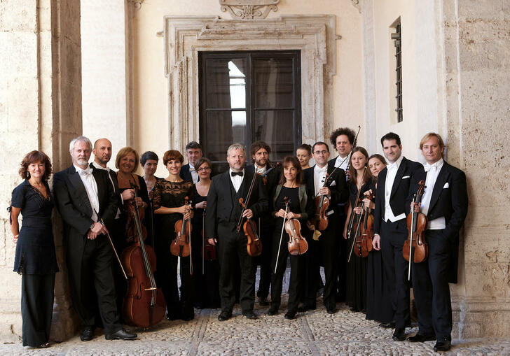 The members of Europa Galante standing in a line holding their instruments