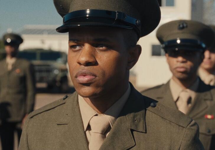 A young stands in a military line up in uniform.