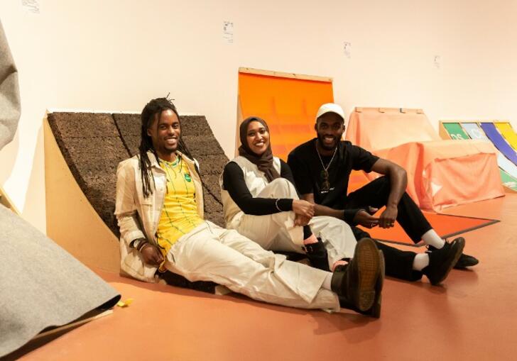 a photo of RESOLVE Collective sitting on their installation in The Curve gallery for them's the breaks