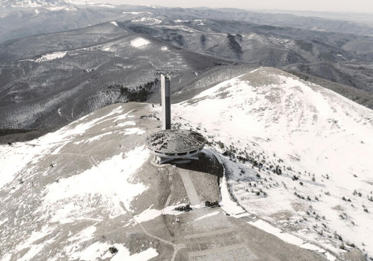 Arial shot of a large industrial building surrounded by snow covered mountains in a still from The Gift.