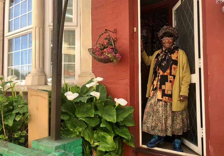 A woman stands in front of her house in a still from Feeding Lewisham