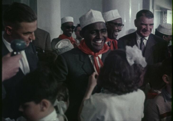 A girl ties a red scarf around a man's neck in a still from Red Africa