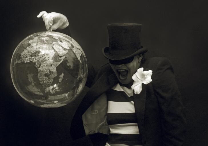 black and white photo of Carie Mae Weems in a top hat, holding up a globe