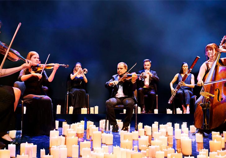 Musicians from the Mozart Festival Orchestra performing while surrounded by candles at their feet