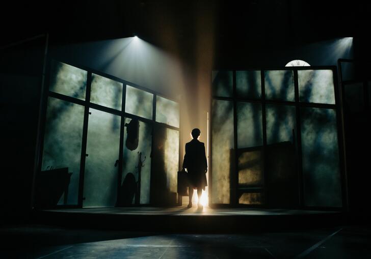 Still of someone standing in the shadows on a dynamically framed stage