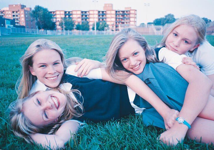 A group of sisters lay in the grass wearing school uniform