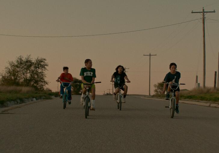 A group of boys ride bikes during sunset in a still from War Pony