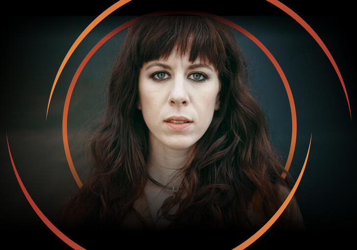 Missy Mazzoli looking at the camera, with circular orange swirls around her head