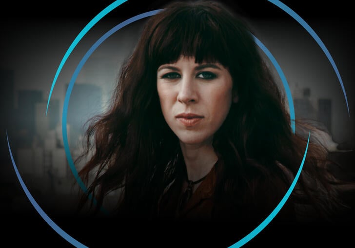 Missy Mazzoli looking at the camera, with circular blue swirls around her head