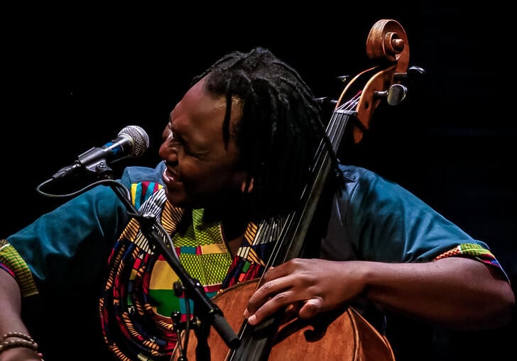 Abel Selaocoe playing his cello against a black background