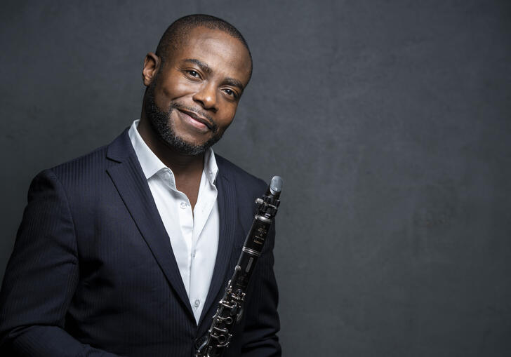 Anthony McGill smiling at the camera while holding his clarinet