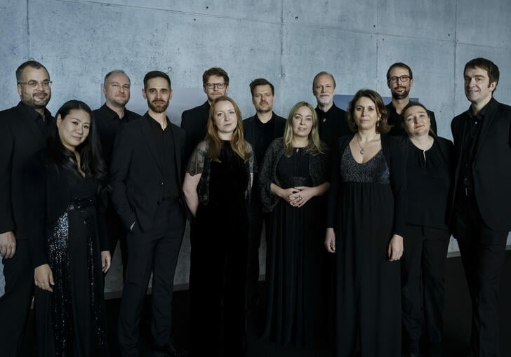 Members from Collegium Vocale Gent dressed in black, standing in front of a concrete wall