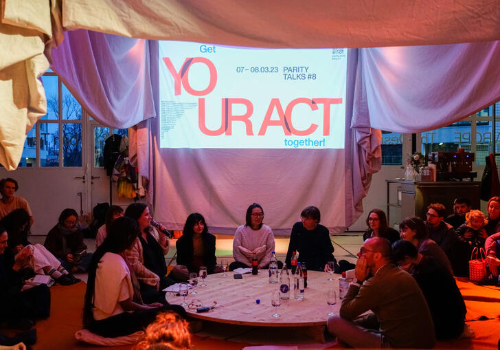 Group of people seated on the floor around a round table