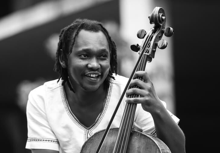 Black and white photo of Abel Selaocoe holding his cello