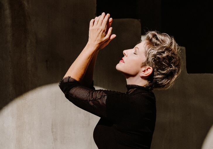 Side profile of Joyce DiDonato with her hands clasped and raised upwards