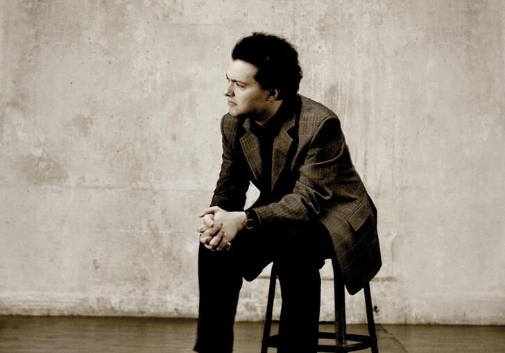 Evgeny Kissin sitting on a stool with his hands clasped