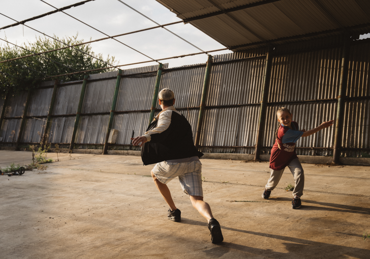 A young father runs with his young daughter in an abandoned warehouse