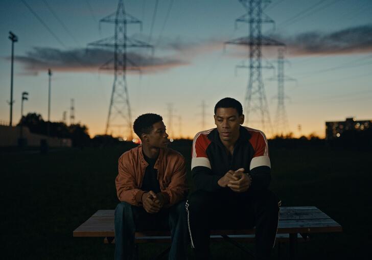 Two brothers sit on a wall against a sunset backdrop. 