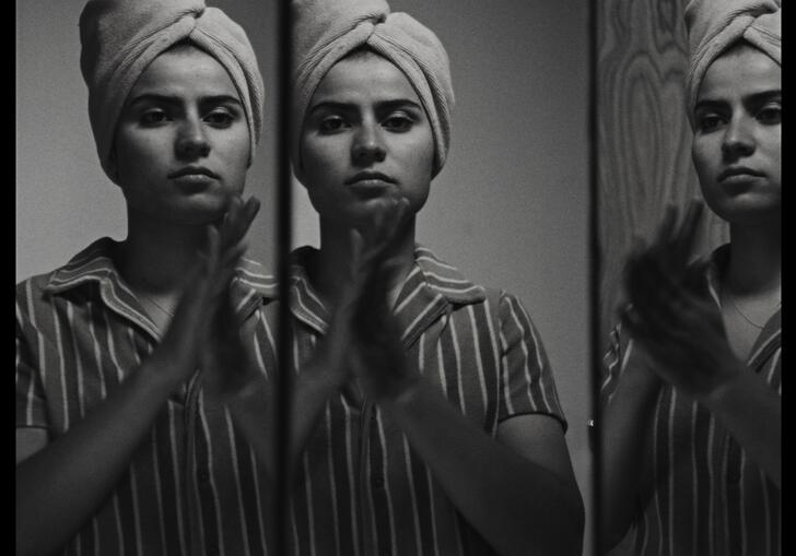 Three frames of a woman with fabric wrapped around her head looking forward, perhaps into a mirror.