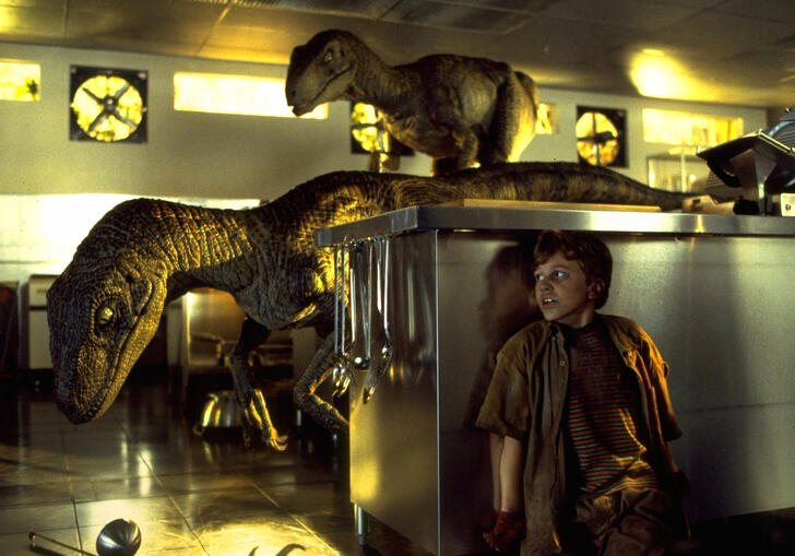 A boy cowers away from dinosaurs