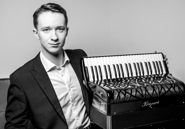 Black and white photo of Ryan Corbett sitting next to an accordion