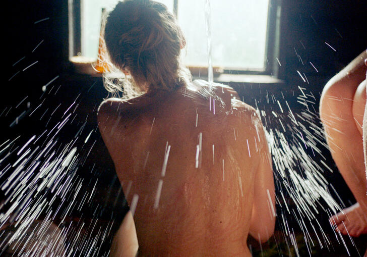 A woman washes her back in a sauna 