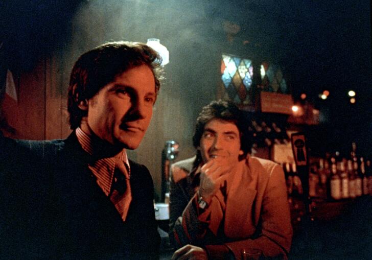 Two men look smug in a smoky 1970s New York bar. 