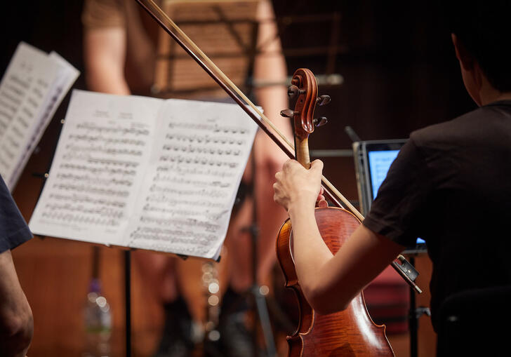 Musician holding a violin, with a music stand and score in background