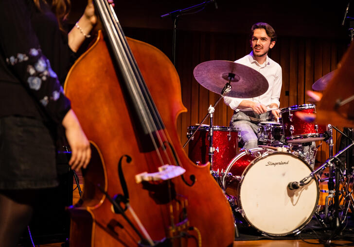 Double bass in foreground and percussionist on drum kit in the background