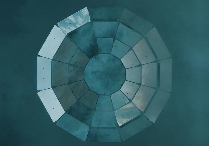 Reflective panels form a circular pattern against a blue smoky background