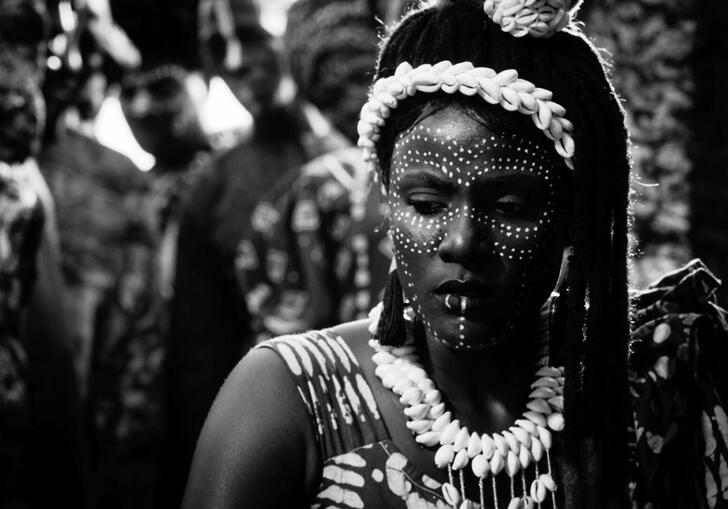 A woman looks pensive in traditional African dress, in a black and white image.