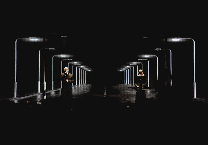 The Pet Shop Boys stand on a dark, elaborately lit stage. 