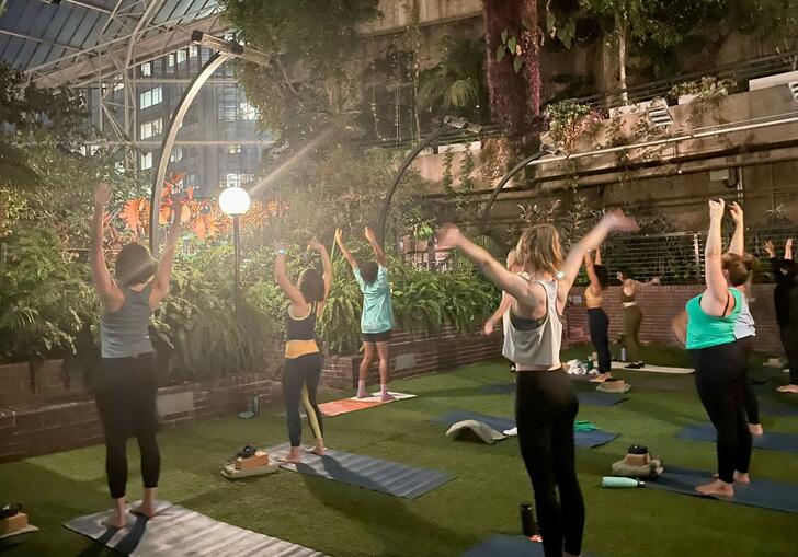 People practicing stretching, led by Tamzin Jade, in the Conservatory. 