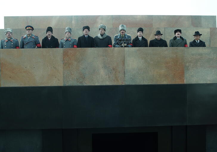Stalin's peers stand on a concrete balcony dressed in military uniform