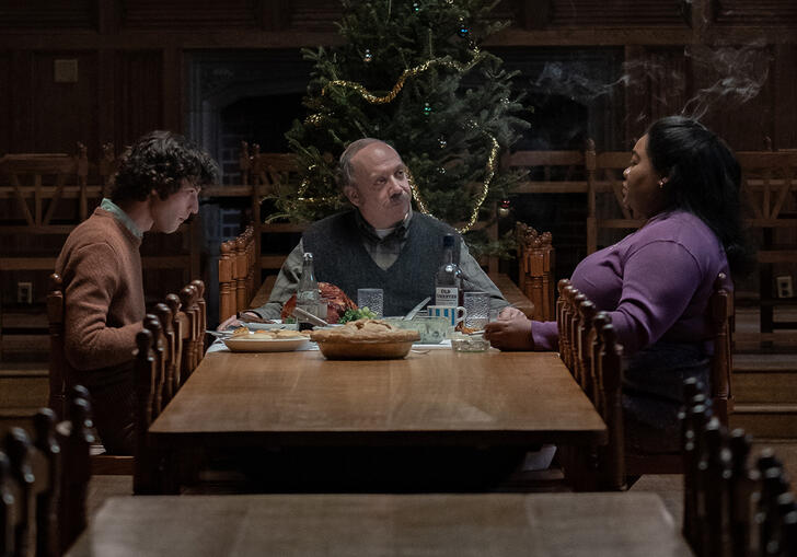 The people sit round a kitchen table having a Christmas dinner.