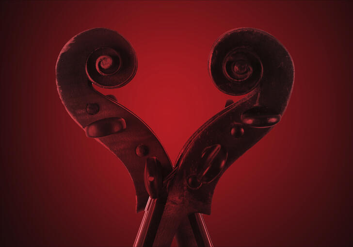 The scrolls of two violins next to each other, forming a love-heart shape. There is a red wash over the image.