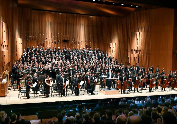 The Westminster School Symphony Orchestra and Choir, musicians from the Westminster Choral Society, Pimlico Musical Foundation and Tri-borough Music Hub standing on stage in the Barbican Hall