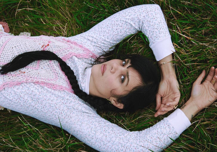Natasha Khan lies on grass with her arms above her head