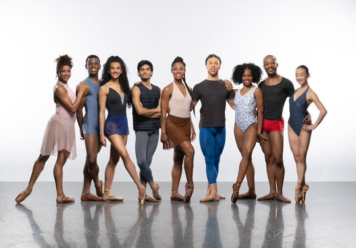 Members of the Ballet Black company pose in a line, they smile at the camera. 