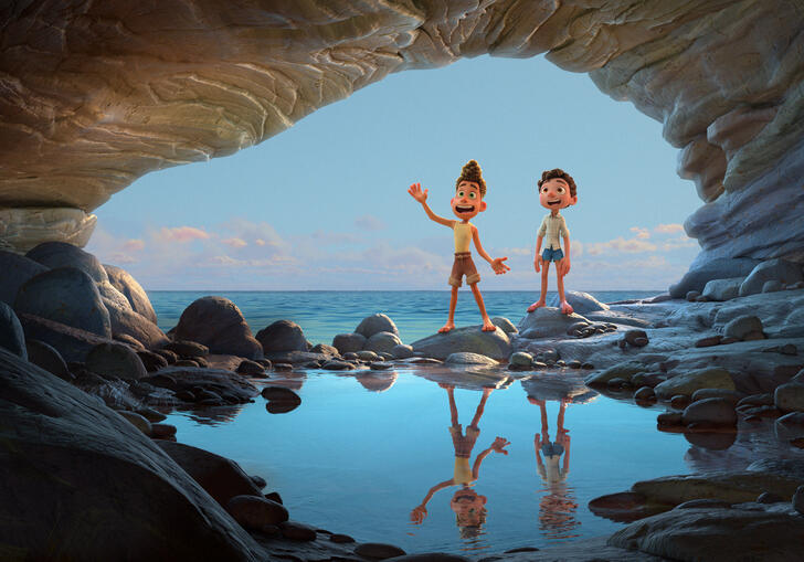 Two young boys stand in a cave by the ocean.