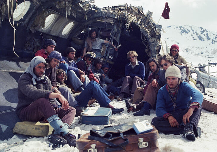 The plane crash survivors sit in the snowy wreckage