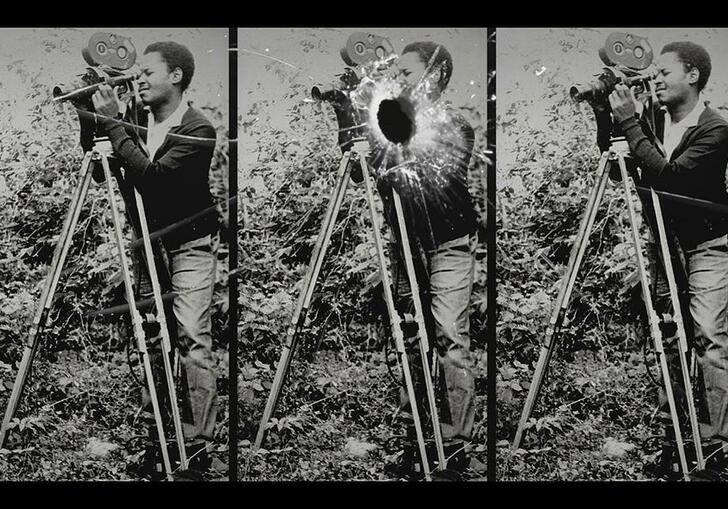 A crop of a film reel, depicting three black and white images of a man looking through a film camera that is mounted on a tripod. The central image has a bullet hole in it.