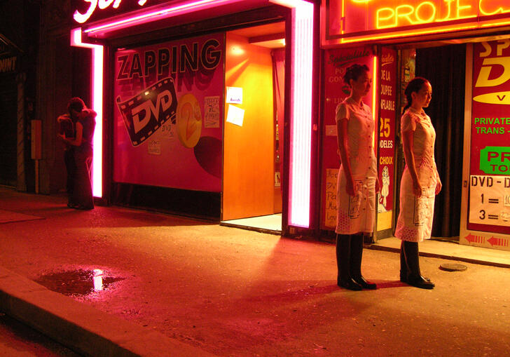 Two people look on in a neon soaked street