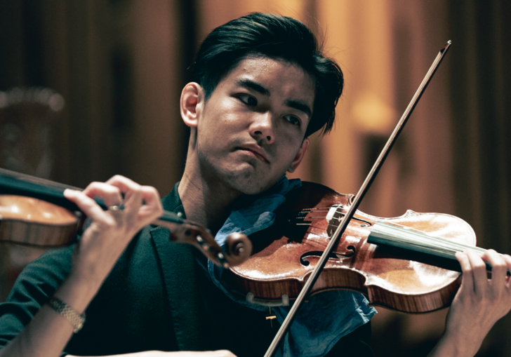 A close up shot of a violinist playing his violin on stage