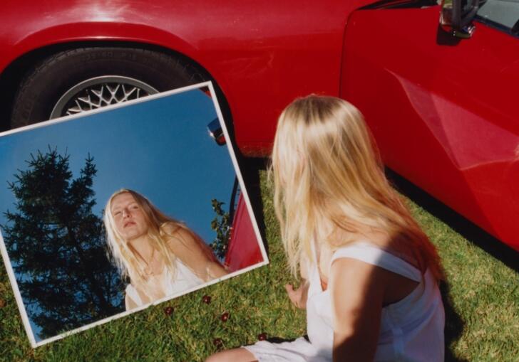 Billie Marten sits on the floor looking in a mirror