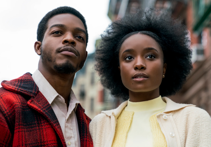 A man and a woman stand in an urban American street, looking forward.