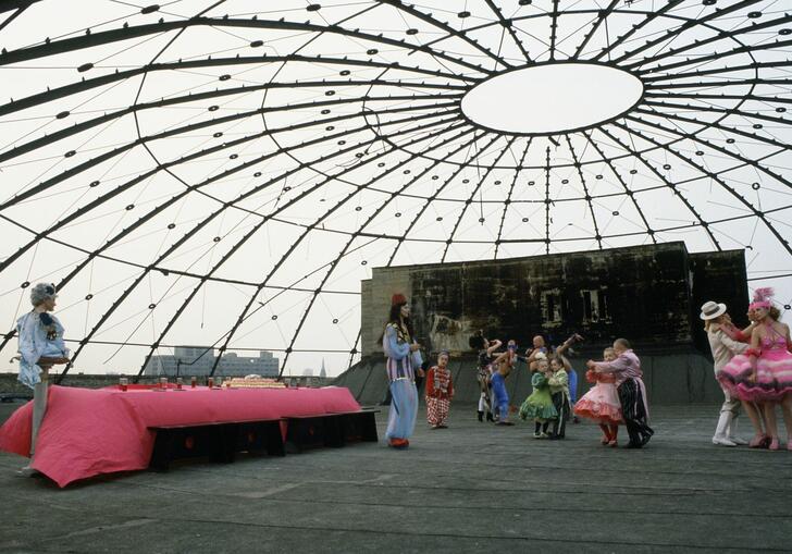A group of people dance in a large dome. 